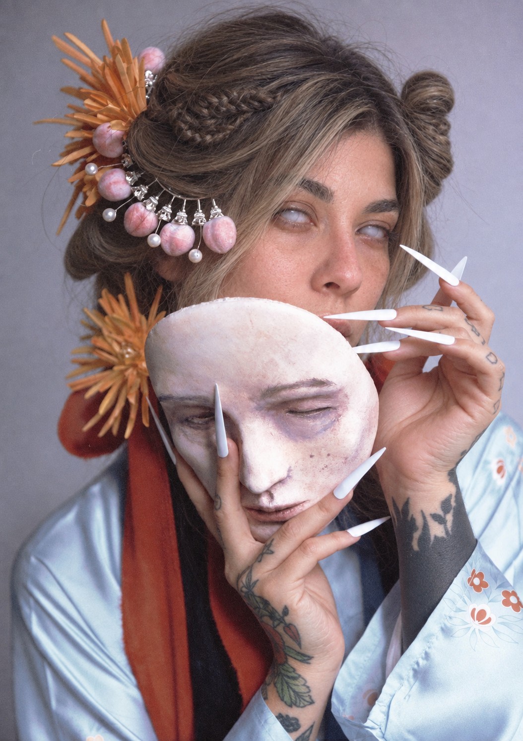 Laurent Alba in a blue kimono holding a pale theatrical mask