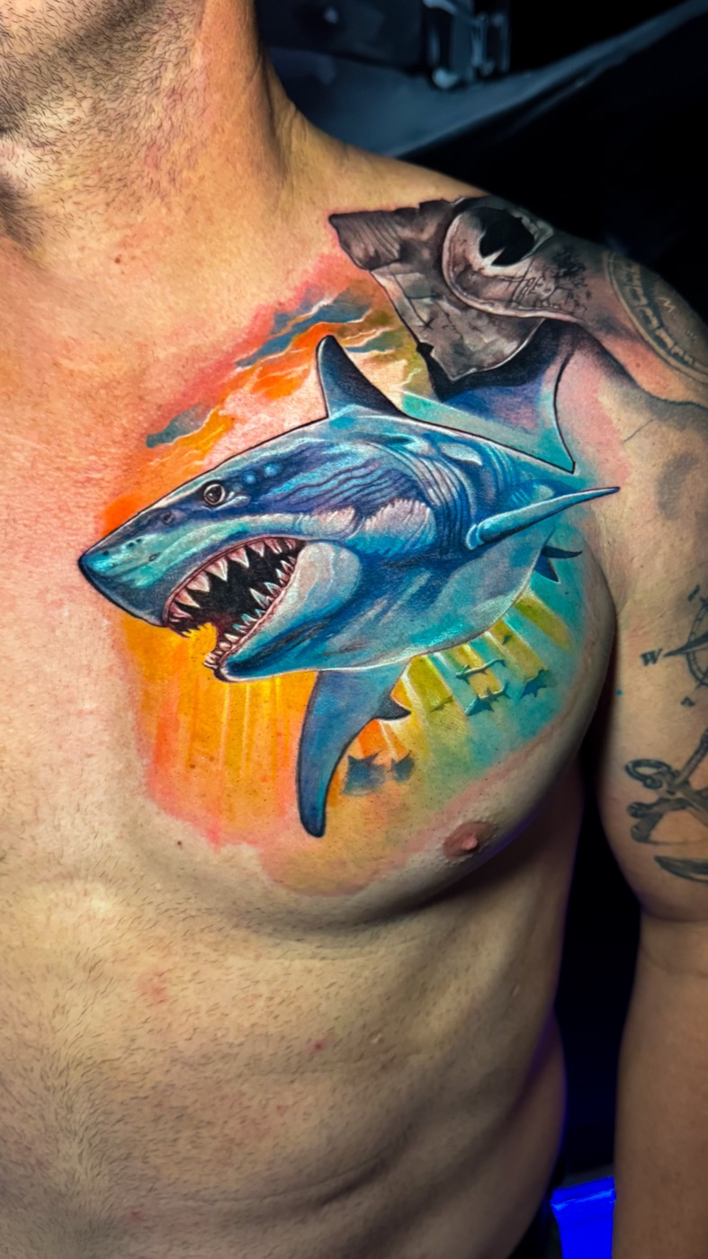 Blue and turquoise shark chest tattoo against an orange and yellow background